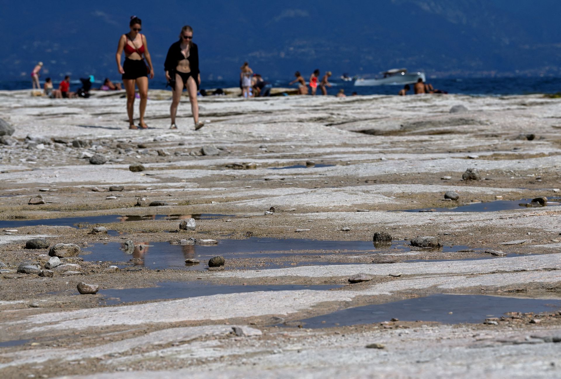 Turistas y locales caminando sobre el lago seco de Italia durante una de sus peores sequías en el año. - Foto Flavio Lo Scalzo/Reuters