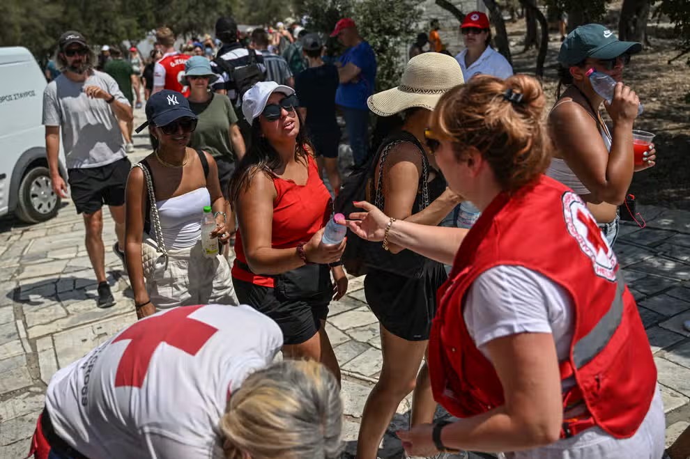 Miembros de la Cruz Roja dando botellas de agua a turistas en Atenas por el calor extremo. - Foto AFP/Gettyimages