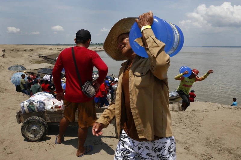 Los residentes tuvieron que cargar sus suministros de vuelta a sus hogares cruzando largas distancias bajo el sol. - Foto Edmar Barros/AP